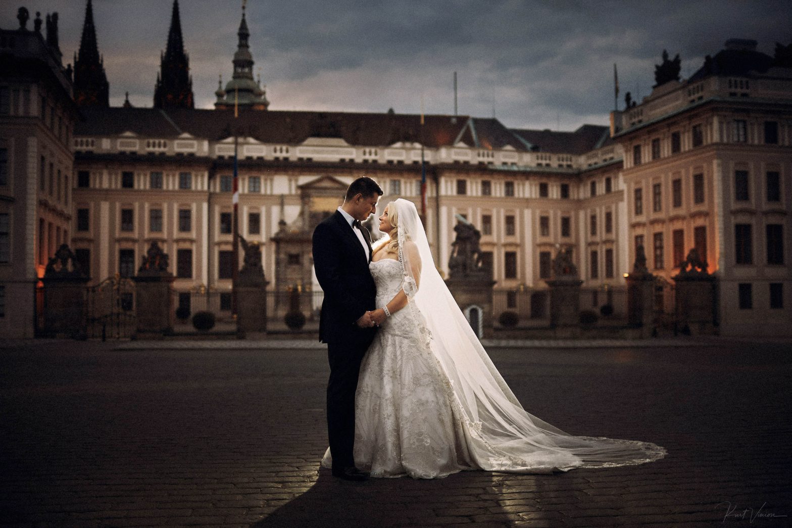 Photo of bride & groom at night in front of Prague Castle