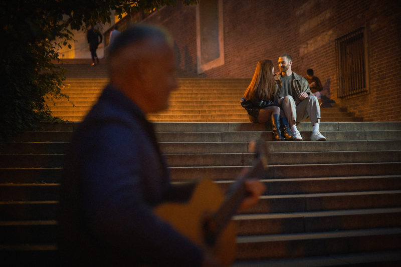 A guitarist performs as Bryanna and Max enjoy the romantic atmosphere following their engagement.